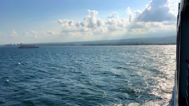 Bali, Indonesia - August 27, 2025: Car and passenger ferries cross the Bali Strait from Gilimanuk Harbor to Ketapang Harbor on the island of Java. View of the strait from the ferry deck. 4K