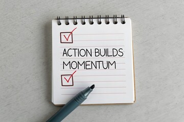 Notepad showing Action Builds Momentum with tick marks and pen