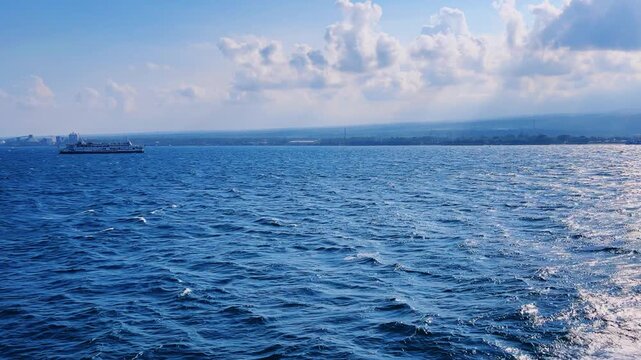 Bali, Indonesia - August 27, 2025: Car and passenger ferries cross the Bali Strait from Gilimanuk Harbor to Ketapang Harbor on the island of Java. View of the strait from the ferry deck. 4K
