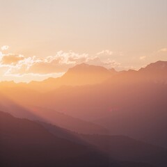 Obraz premium The mountains are covered in clouds and the sun is setting
