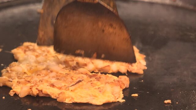 Fried eggs with meat cooking on a large outdoor griddle at a Singapore street food cafe; simple, affordable meal popular with locals, showing casual urban dining and everyday street cuisine.