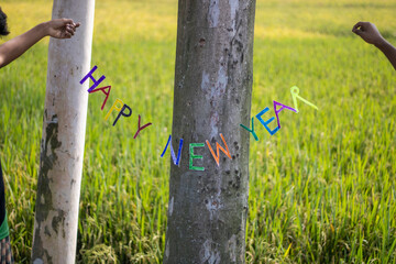 Happy new year message written on trees in a grassy field