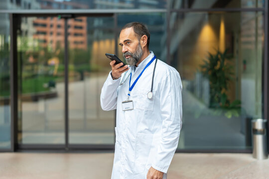 Mature doctor using smartphone for voice message communication - Powered by Adobe