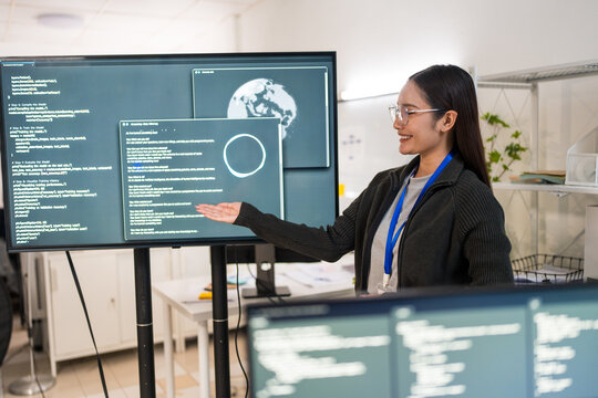 The confident woman presenting coding project at night in office, bright smiles and focused expressions