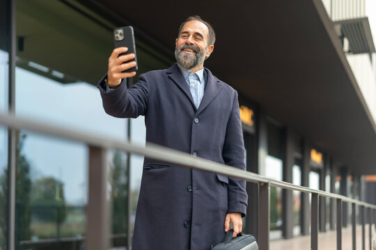 Mature businessman smiling taking a selfie with phone