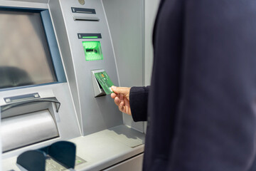 Person inserting credit card into atm slot for banking