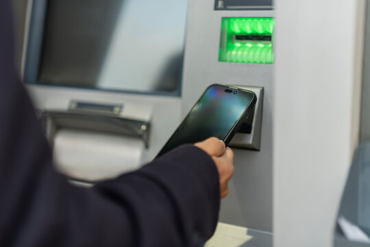 Person using smartphone for contactless atm transaction