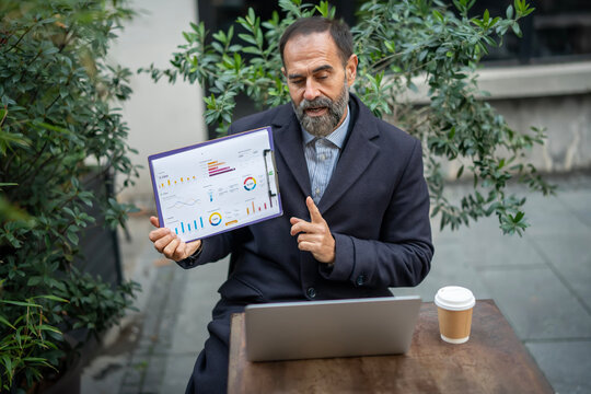 Mature businessman presenting financial data during outdoor video call