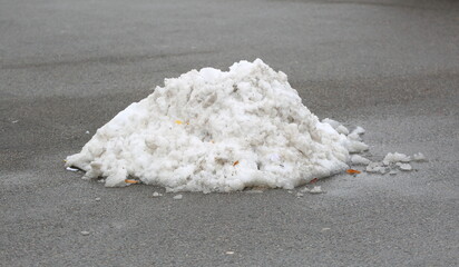 A small pile of snow on the gray asphalt