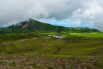 Lush green hillsides around Mt. Aso close to Nakadake Crater with views on the cone of Komezuka crater and other peaks, Kumamoto, Japan