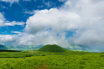 Lush green hillsides around Mt. Aso close to Nakadake Crater with views on the cone of Komezuka crater and other peaks, Kumamoto, Japan
