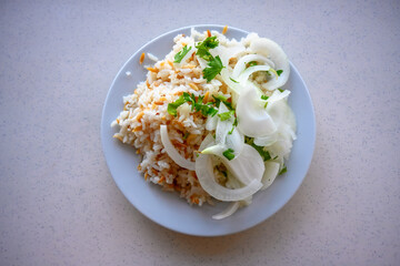Top-down view of traditional Turkish rice pilaf (Pilav) with vermicelli, garnished with sliced onions and parsley on a white plate.