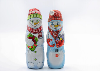 Chocolate snowmans wrapped in festive foil packaging closeup on white.