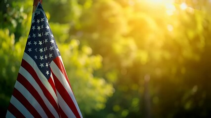 A closeup of an American flag against a backdrop of a lush green forest. The flag is prominently displayed, with its iconic red and white stripes and blue field with white stars.