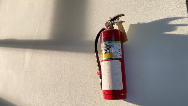 Hand holding a red fire extinguisher for safety and emergency protection