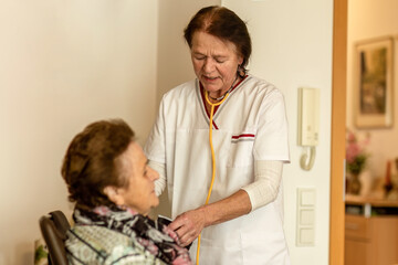 Obraz premium A home care nurse measures an elderly woman’s blood pressure as part of cardiovascular health monitoring.