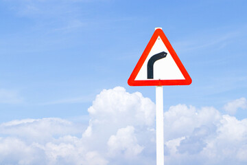 Dangerous bend to right, triangular warning traffic sign indicating sharp curve with blue sky cloud white is background. Concept for road safety, driving caution alerts. Watch out for right curve.