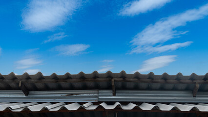 Two plane metal sheet roof for sun protection and rain protection. Under blue sky and white clouds.