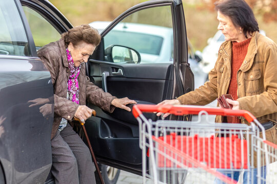 Elderly woman supported by her daughter while shopping, family caregiving and daily assistance