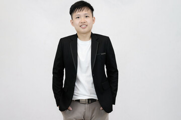 A cheerful and relaxed young Asian professional or student standing with hands in their pockets, smiling comfortably against a clean white studio background