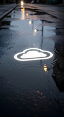 A glowing cloud icon on a wet street surface during rainy weather, illuminated by streetlights reflecting on the water
