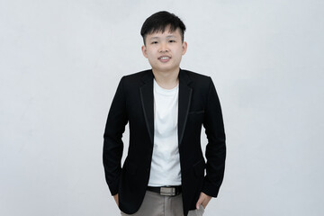 A cheerful and relaxed young Asian professional or student standing with hands in their pockets, smiling comfortably against a clean white studio background
