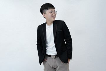 A cheerful and relaxed young Asian professional or student standing with hands in their pockets, smiling comfortably against a clean white studio background