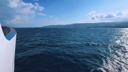 Bali, Indonesia - August 27, 2025: Car and passenger ferries cross the Bali Strait from Gilimanuk Harbor to Ketapang Harbor on the island of Java. View of the strait from the ferry deck. 4K