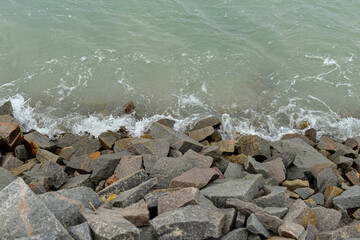 rocky shoreline with gentle water ripples, natural stones meeting calm greenish lake surface, serene outdoor landscape detail with soft textures 