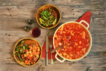 Beef stew served with side dishes and red wine on a rustic wooden table