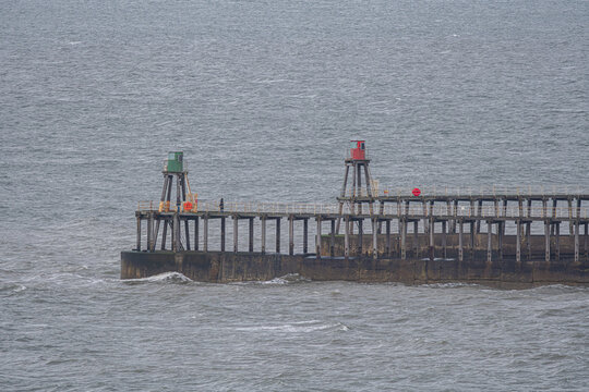 Whitby Pier Beacons &mdash; Red and Green Navigation Lights, Choppy Sea, and Overcast Sky Across Coastal Infrastructure