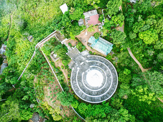 Aerial view of a white Buddhist stupa surrounded by lush green trees