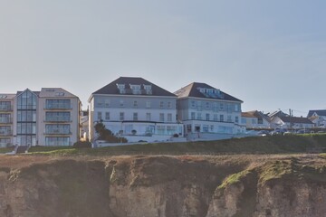 Hotel building on a cliffside. A large, white hotel building with dormer windows is perched on a cliff overlooking the sea in Perranporth - Cornwall - UK