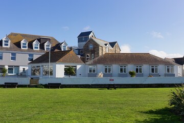 A collection of buildings viewed from a grassy lawn. The buildings are mostly white with varied roof designs in Perranporth - Cornwall - UK