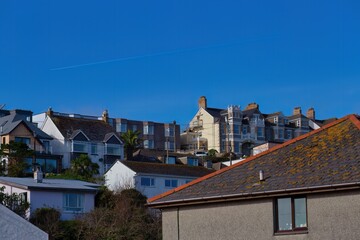 A neighborhood scene with buildings situated on a slight hill, captured under a clear blue sky in Perranporth - Cornwall - UK