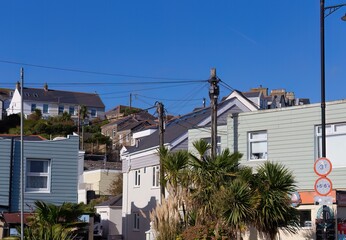 Coastal village buildings ascend a hill under a blue sky in Perranporth - Cornwall - UK