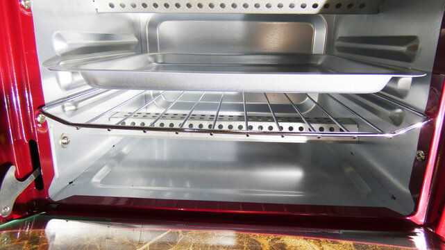Inside a red toaster oven, two racks and a baking tray are visible, highlighting the spacious cooking area suitable for quick meals and snacks, perfect for modern kitchens.