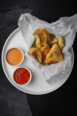 Shrimps in tempura with sauces side by side on a white plate for a menu