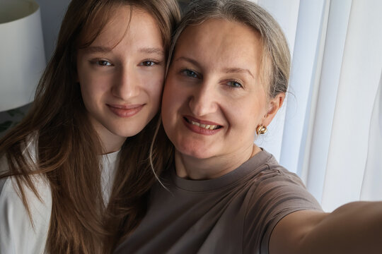 Casual family selfie: cheerful parents and daughter taking a photo together at home, capturing natural joy and lighthearted bonding.