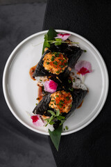 Onigiri with fish filling, drizzled with sauce on a white plate isolated for menu