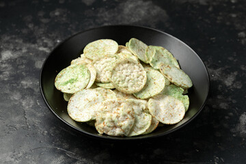 Rice wasabi chips on dark background.