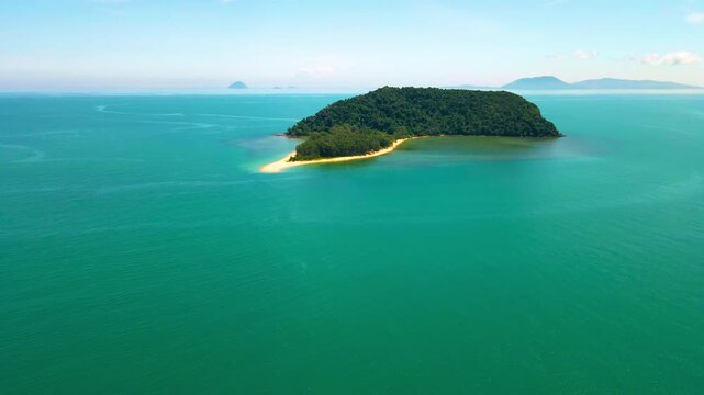Aerial view of a small tropical island located just off the coast of Pantai Bukit Keluang in Besut, Terengganu. The island is covered in dense green forest and surrounded by vibrant turquoise waters.