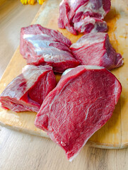 Chunks of raw beef lying on a wooden chopping board, close-up.