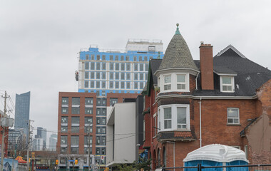 Fototapeta premium contrast of architectural styles: historic house on St Andrew St near Spadina Av and beyond residential buildings and a skyscraper condo in Toronto