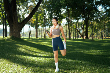 Woman stretching in park checking phone for fitness app
