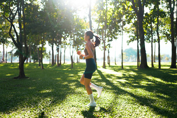 Woman running in park with sunlight creating long shadows