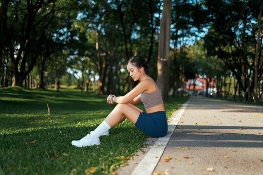 Young woman taking fitness break checking smartwatch in park