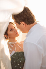 Bride and groom kissing at sunset holding a creative wedding bouquet made of broccoli decorated with pearls, romantic and humorous moment
