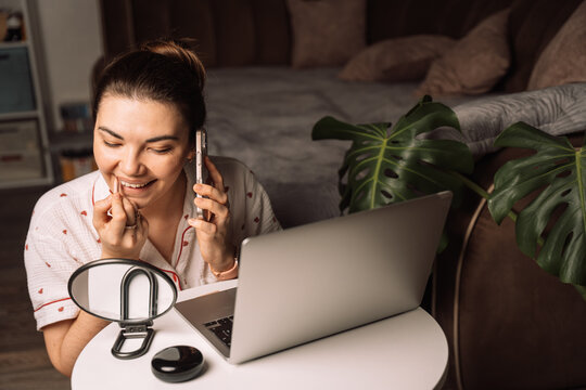 Woman applying lip liner while talking on smartphone. High quality photo