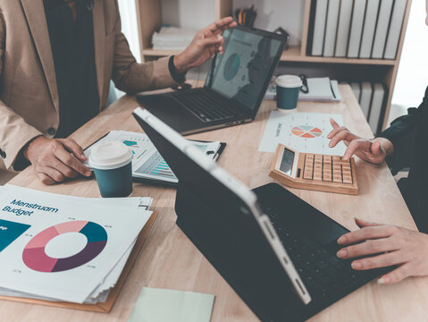 A statistician is preparing charts and documents for a meeting. A team of professionals is reviewing financial documents. Pointing to charts on the desk. Working.